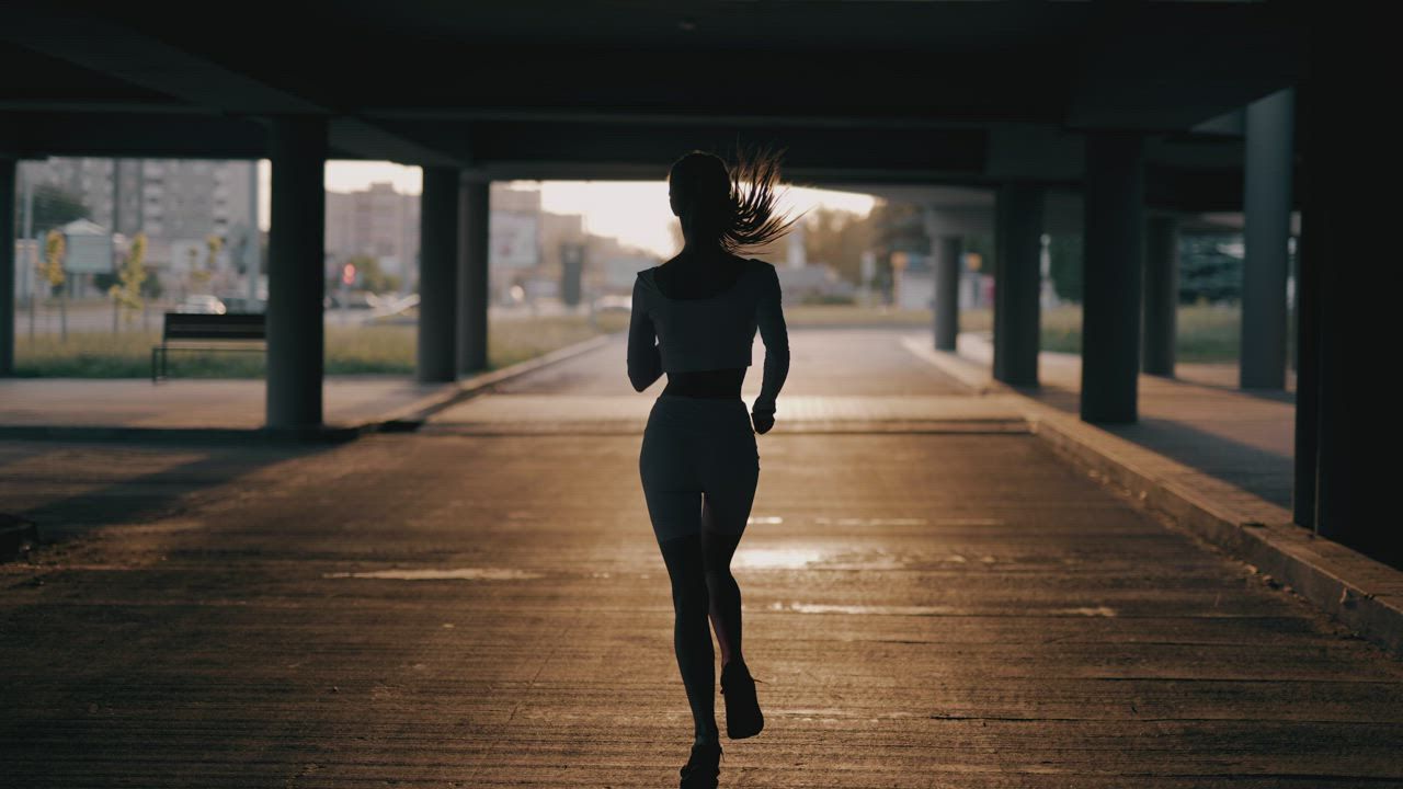 Runner under a city bridge at sunrise