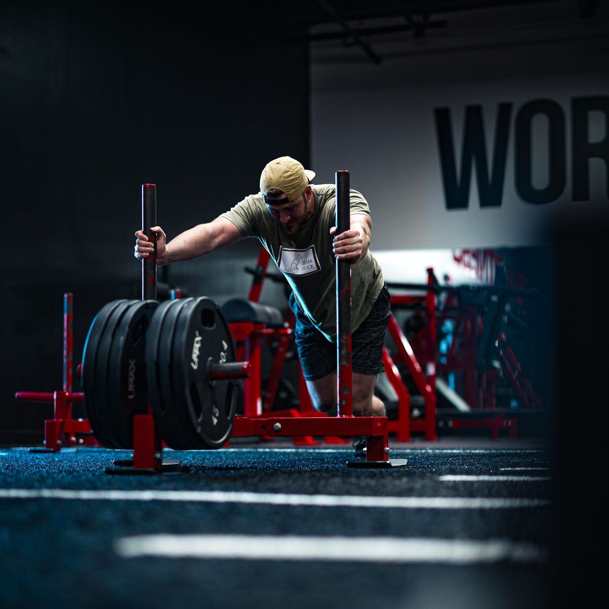 Athlete pushing a weighted sled in a dark gym
