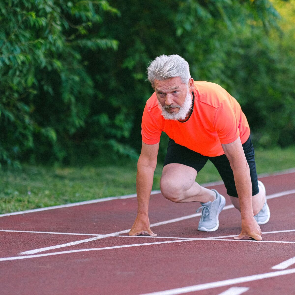 Older athlete crouched at the start line of a running track