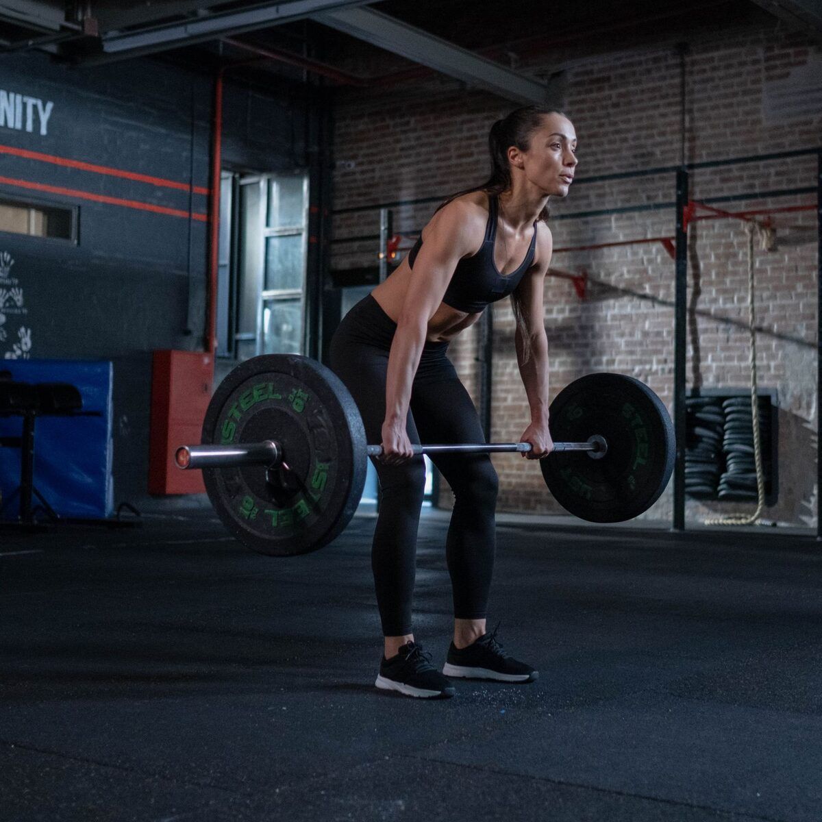 Athlete setting up a barbell deadlift in a brick-walled gym