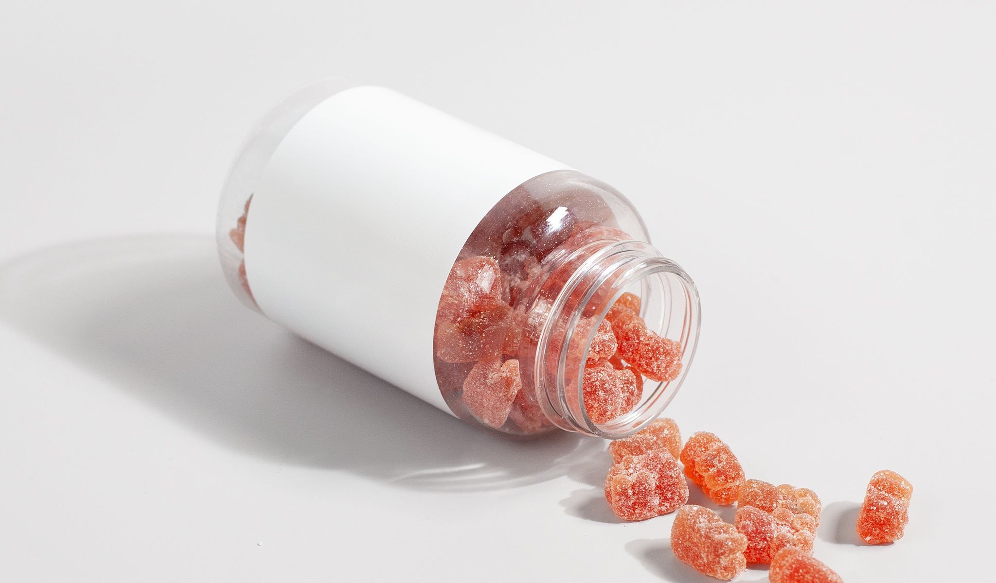 Gummies spilling from a white supplement bottle