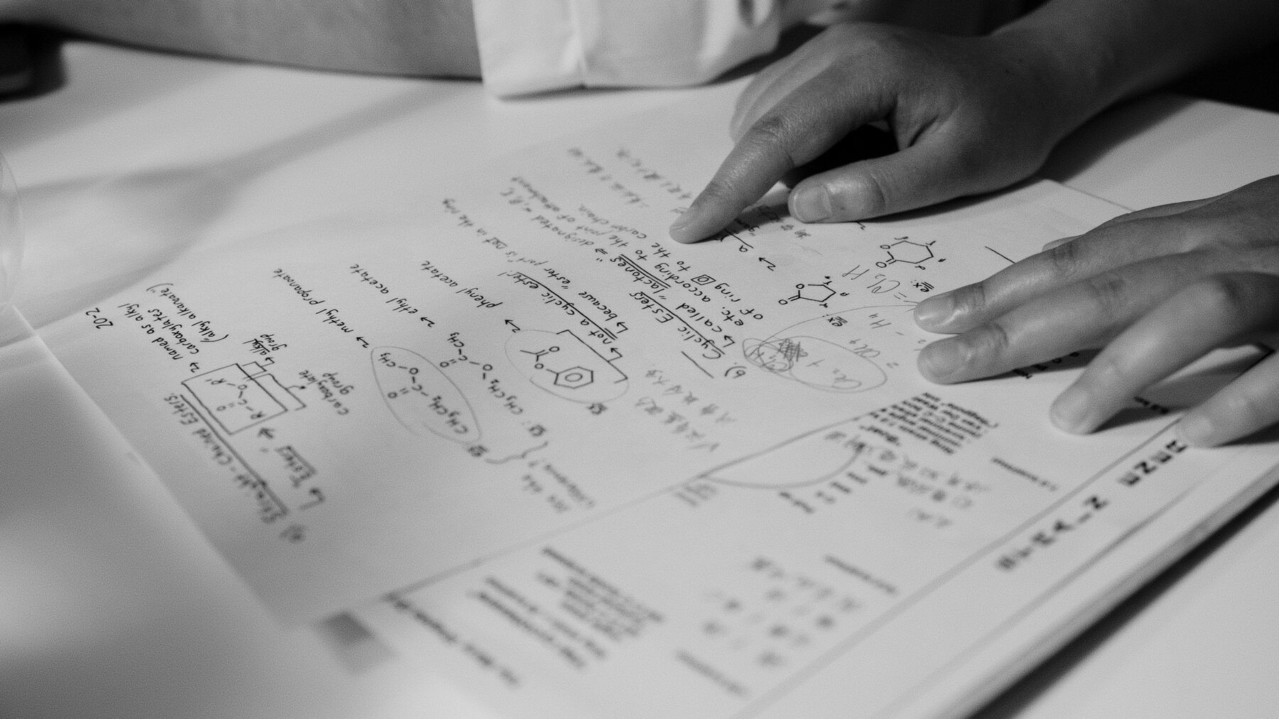 Hands resting on handwritten chemistry notes